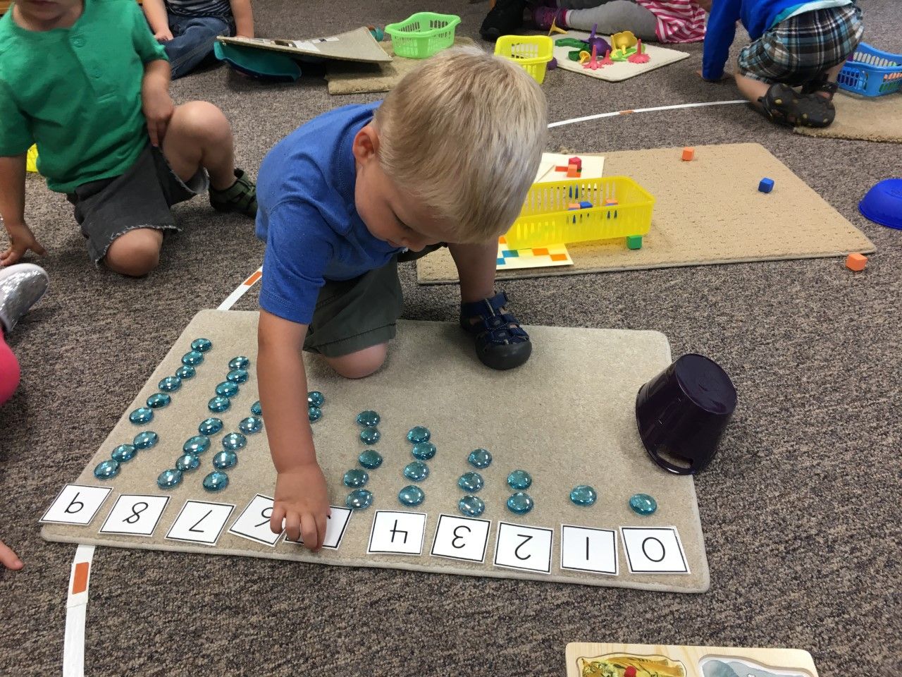 A young boy is playing with numbers on the floor.