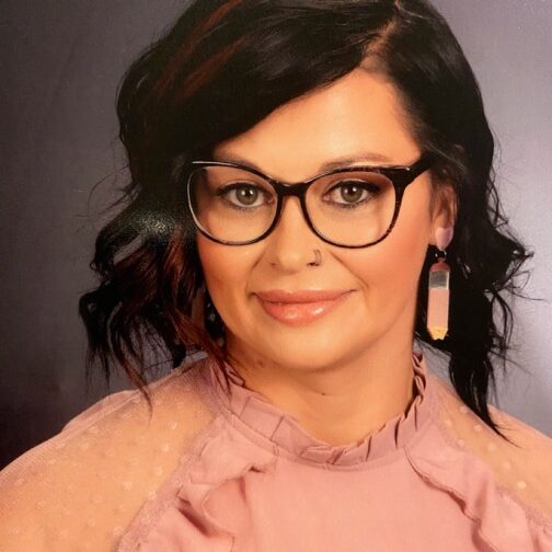 A woman with glasses and black hair wearing pink.